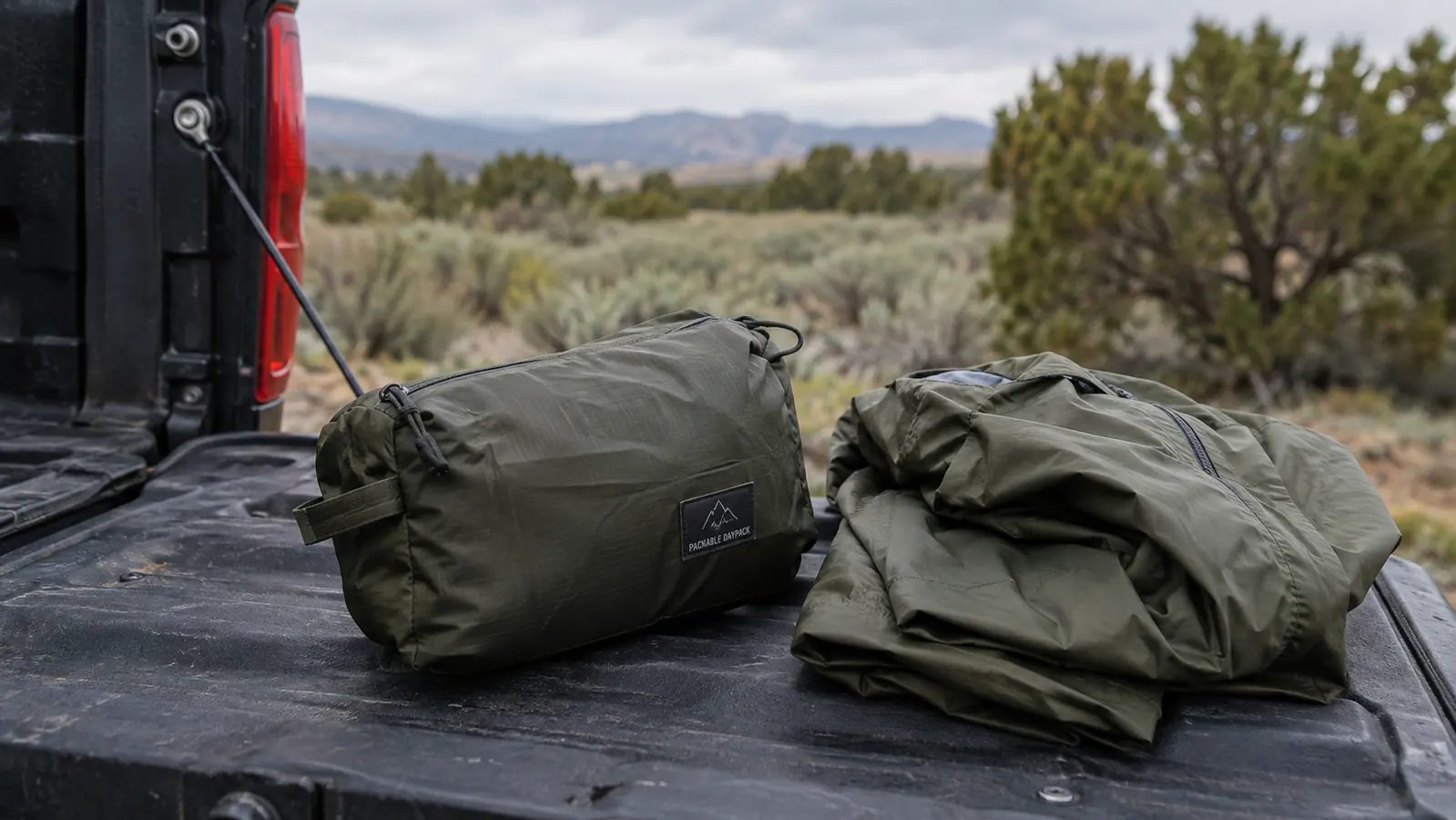 A folded packable daypack on a truck tailgate beside a rain shell